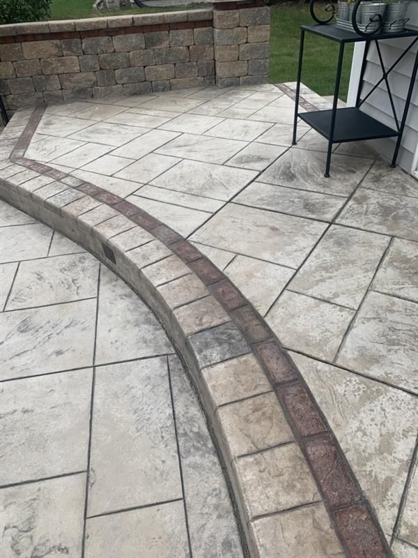 Concrete patio with a curved brick border.