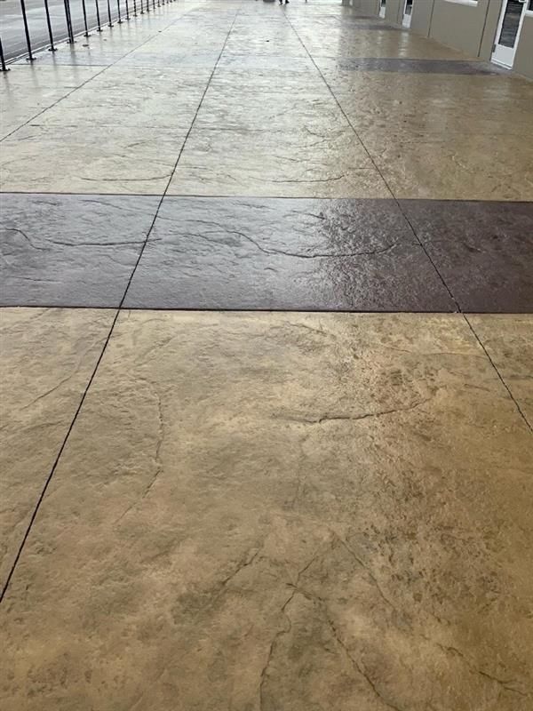 Beige and brown stamped concrete walkway, with a dark brown rectangular accent.