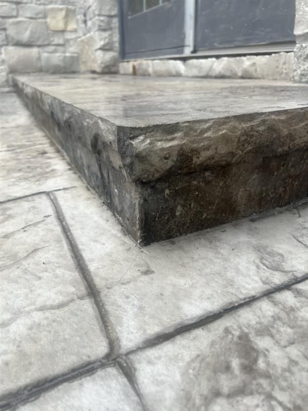 Concrete steps with textured stone pattern, leading to a door.