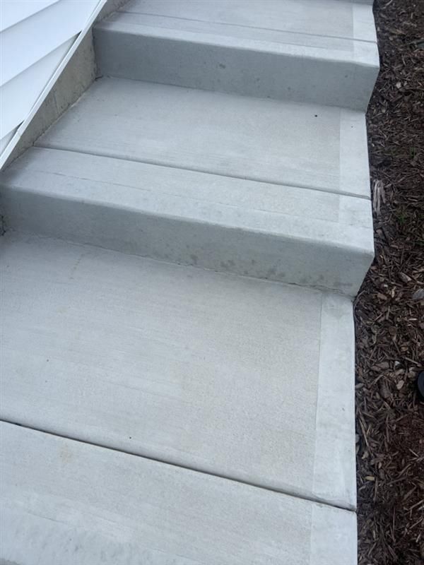 Concrete steps leading down; gray with visible horizontal lines. Brown mulch alongside the steps.