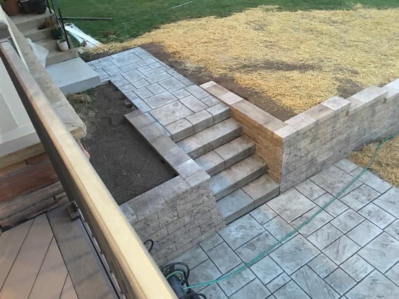 Stone steps and pathway leading up from a patio to a higher level with retaining walls and grass.