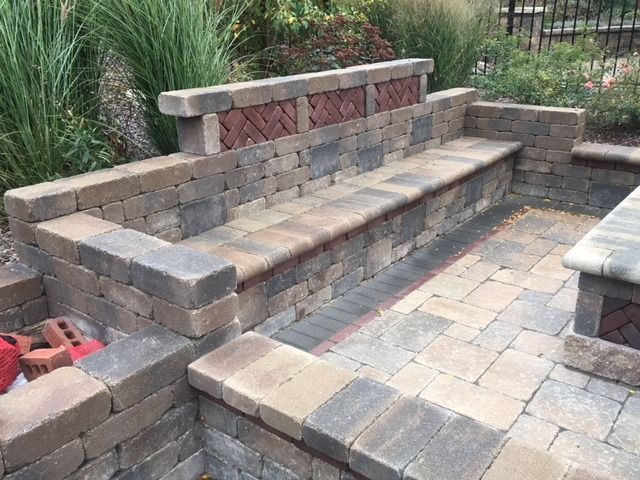 Stone seating built into a patio area with brick accents and a fire pit.