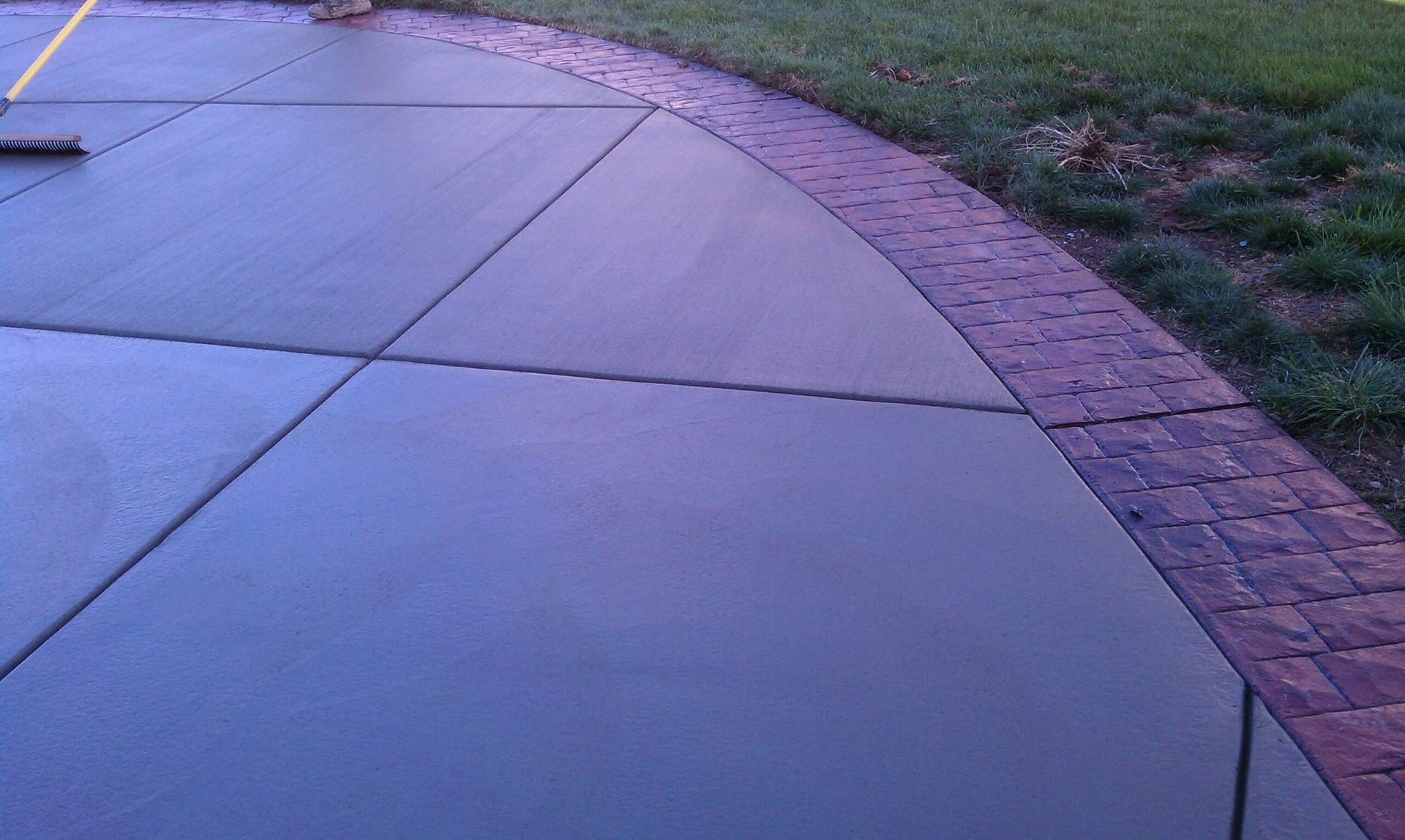 Concrete patio with brick border and grass.