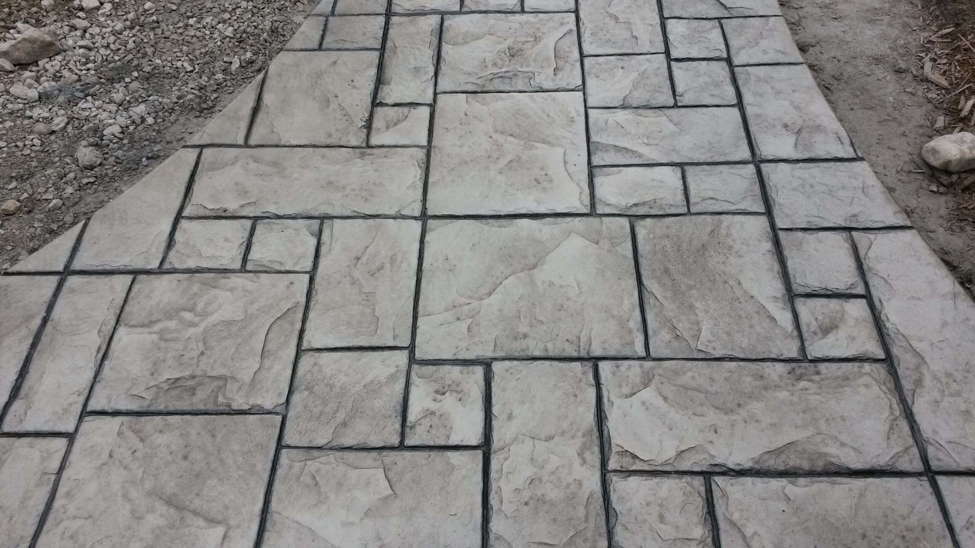 Stamped concrete walkway with a stone pattern. Gray and black.