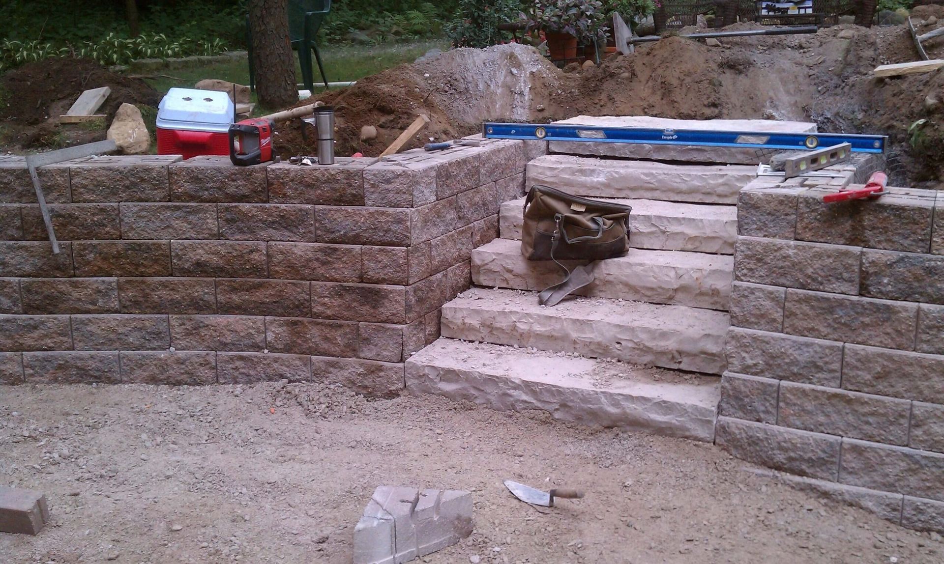 Stone steps and retaining wall under construction in a yard.