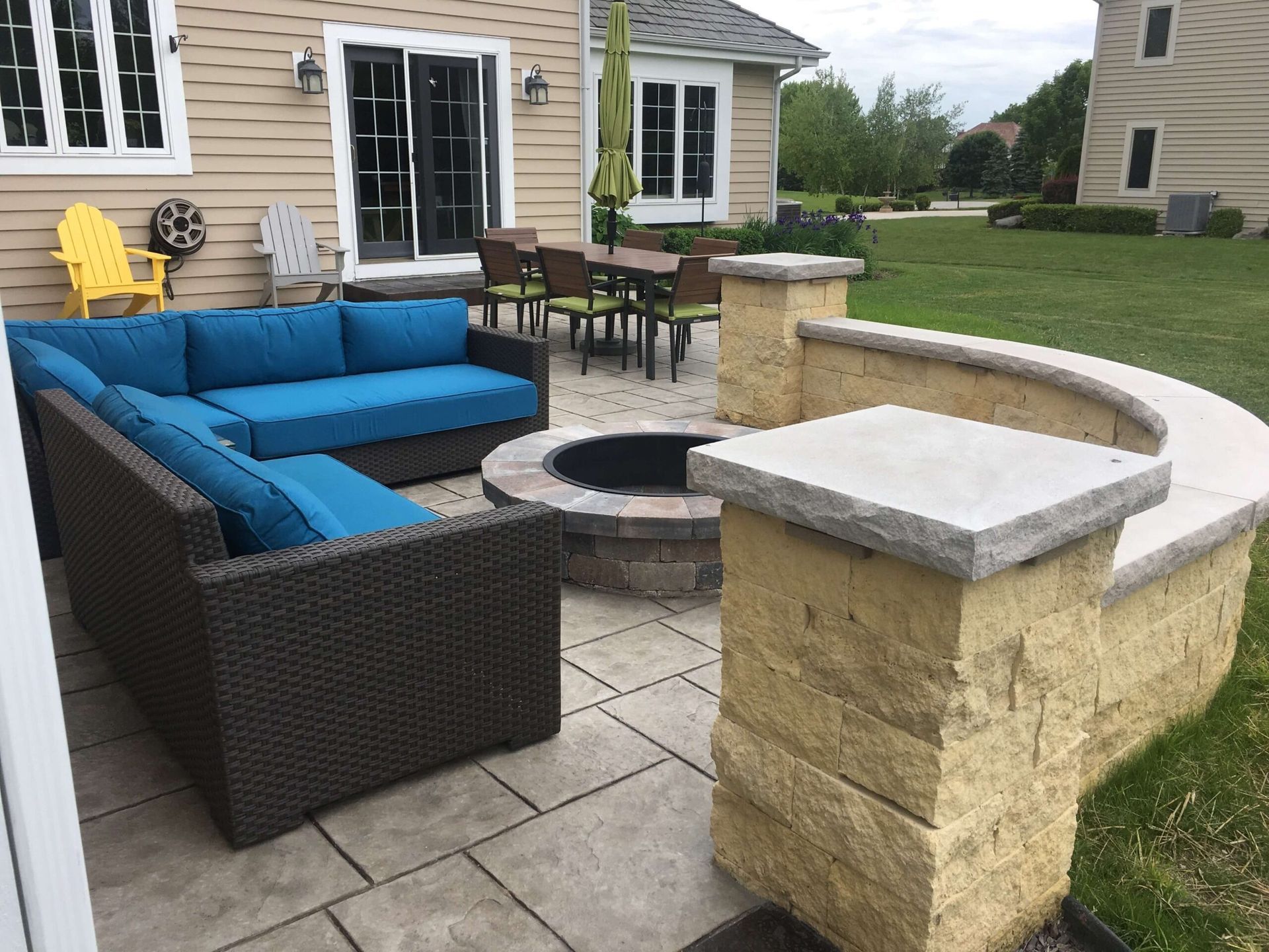 Outdoor patio with blue sectional sofa, fire pit, and dining set.