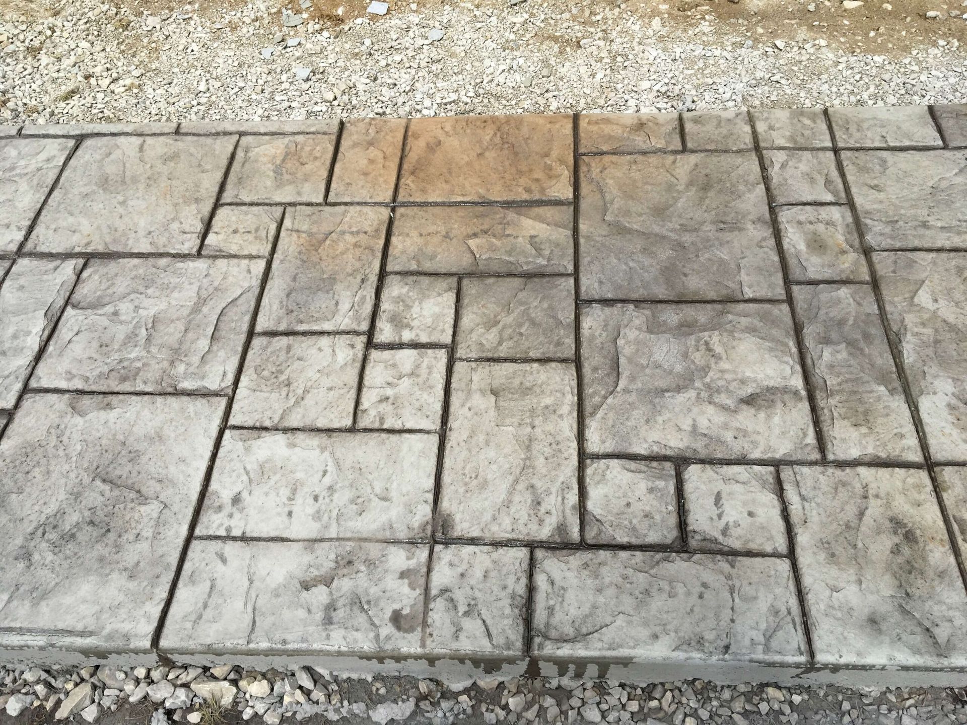 Stamped concrete walkway with a stone pattern; gray and tan hues.