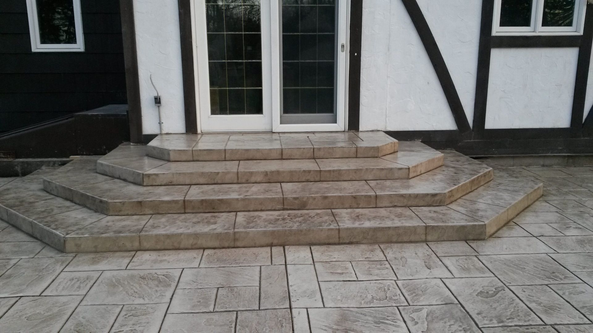 Concrete steps leading to French doors on a house with white and brown exterior.