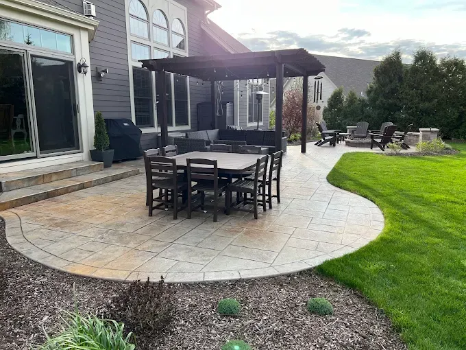 Outdoor patio with dining and seating areas, pergola, and green lawn.