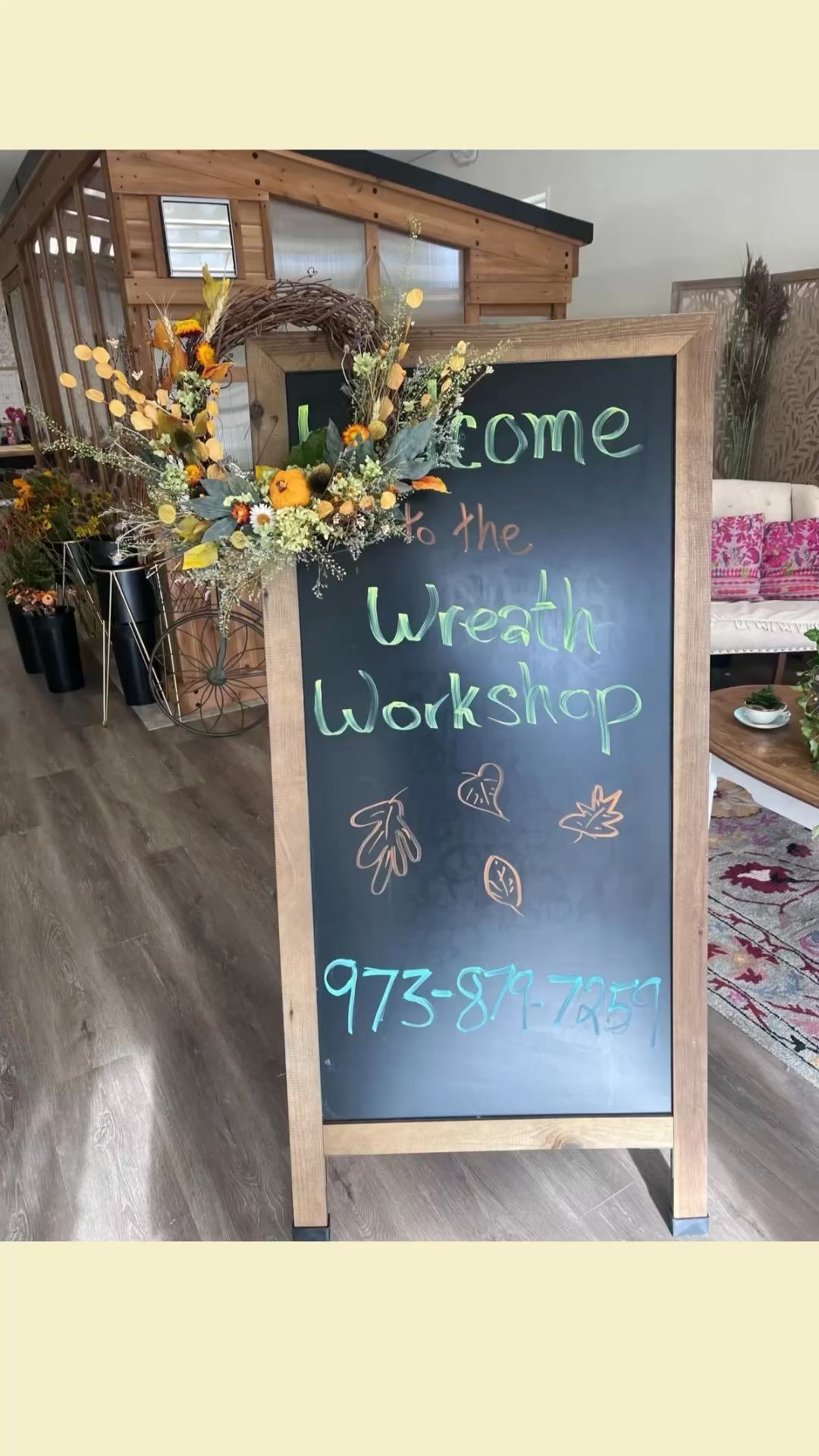 A blackboard in a living room that says `` welcome to the wreath workshop ''.