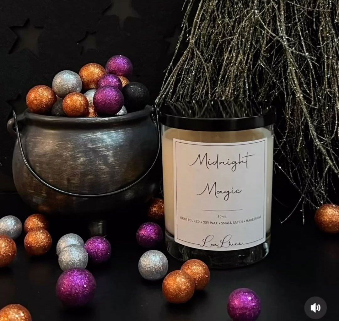 A jar of midnight magic candle next to a cauldron filled with glitter balls