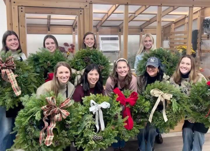 A group of women are posing for a picture while holding christmas wreaths.