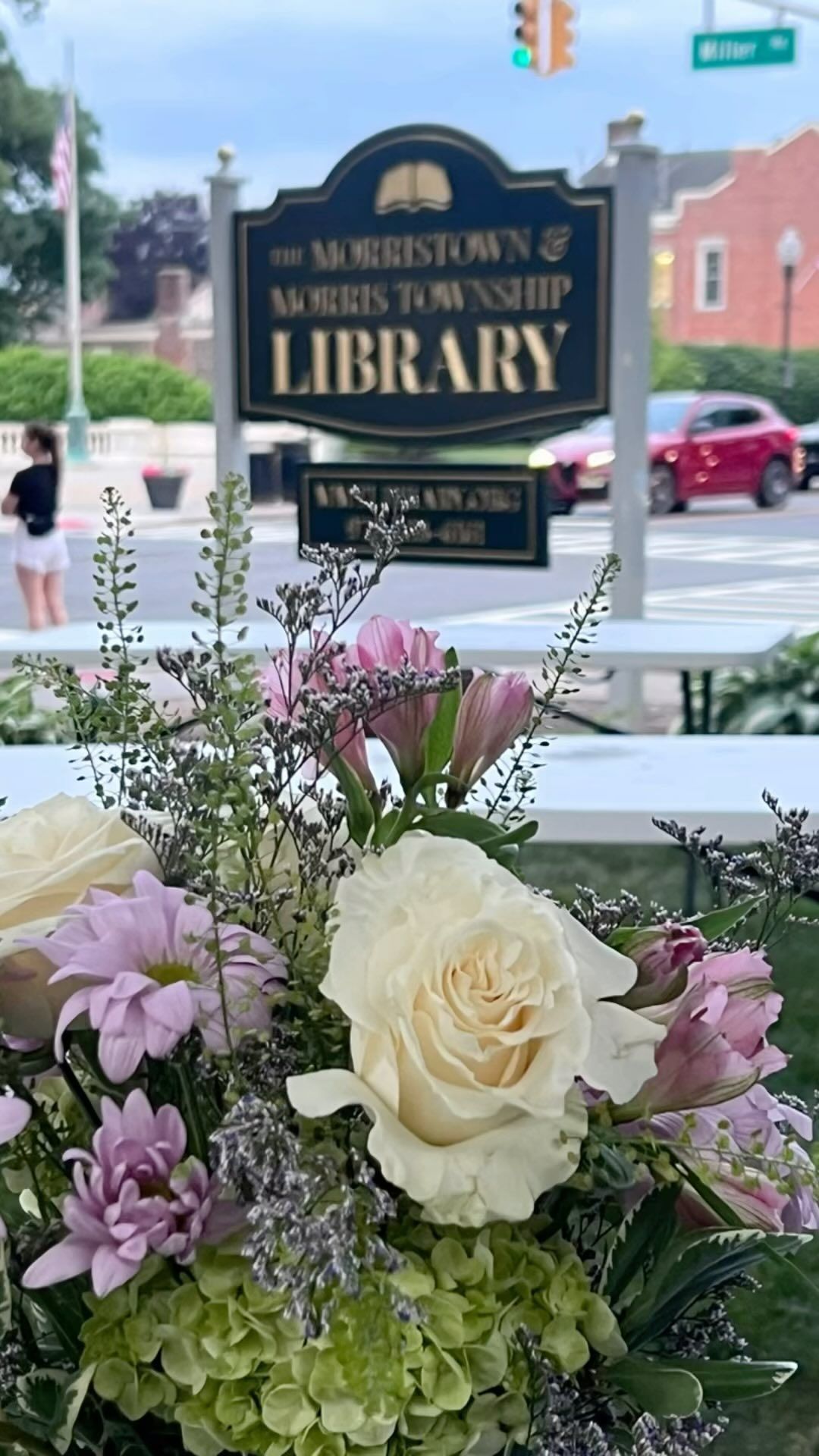 A sign for the library is behind a bouquet of flowers.