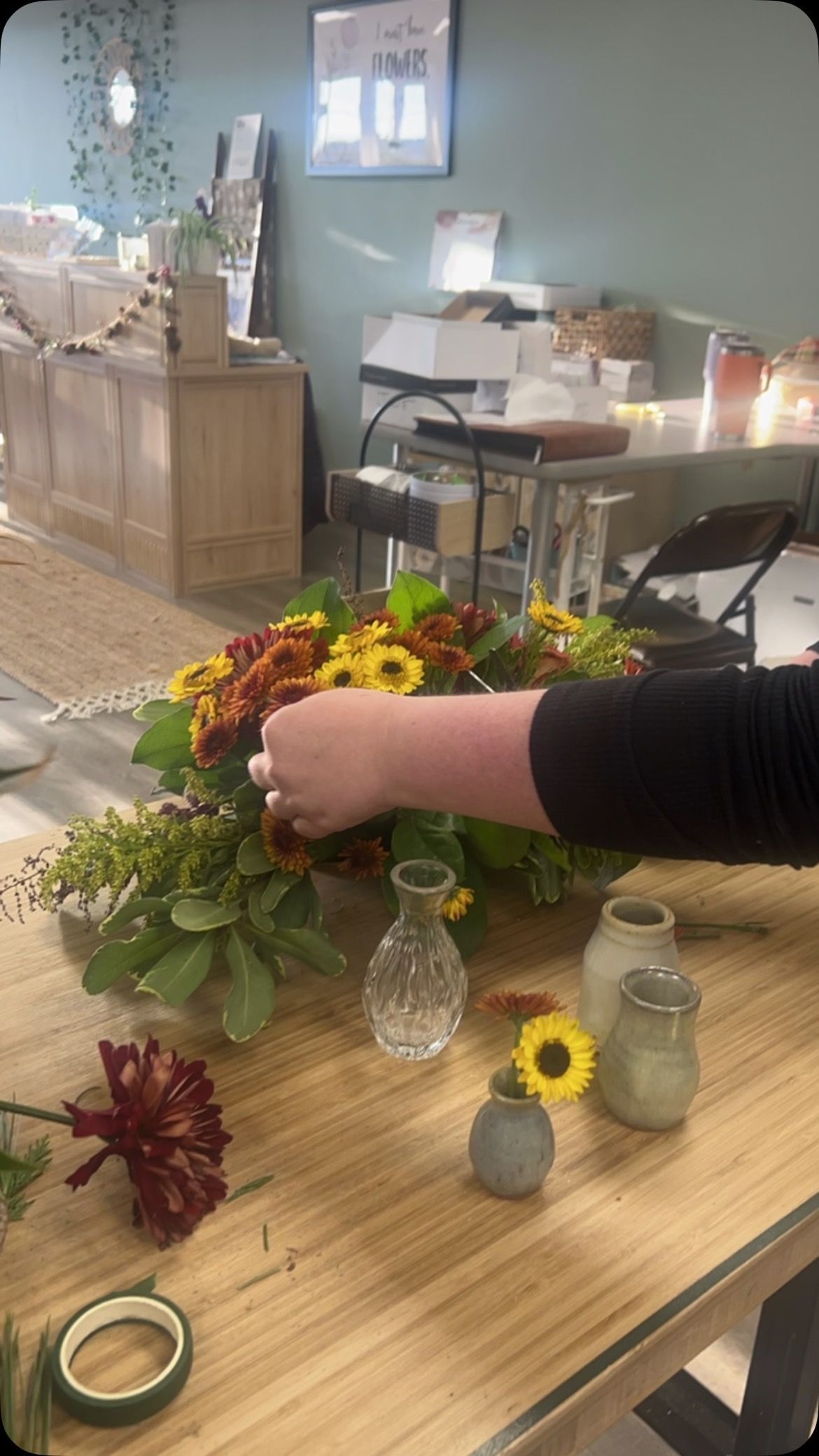 A person is making a bouquet of flowers on a wooden table.