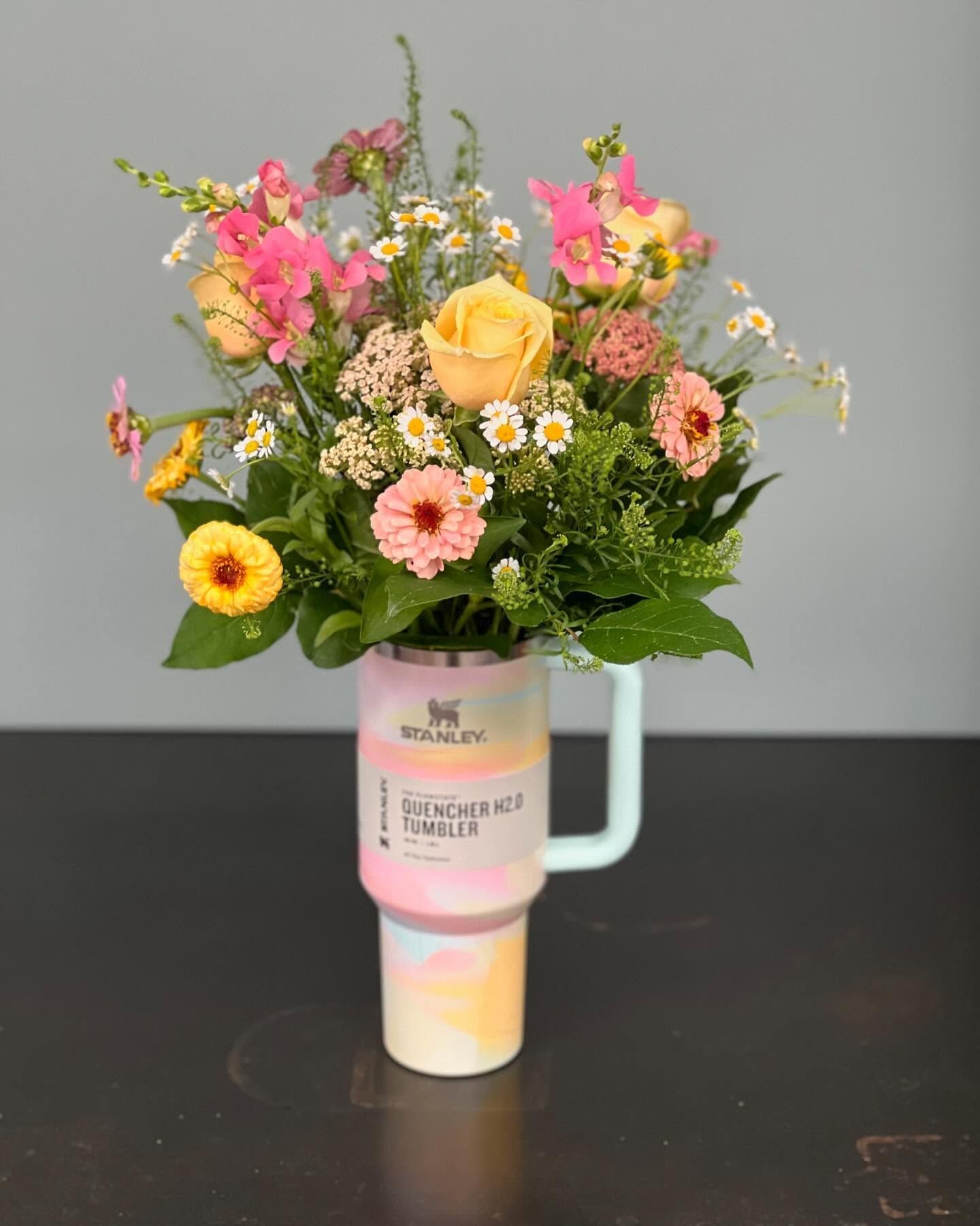 A mug filled with flowers is sitting on a table.