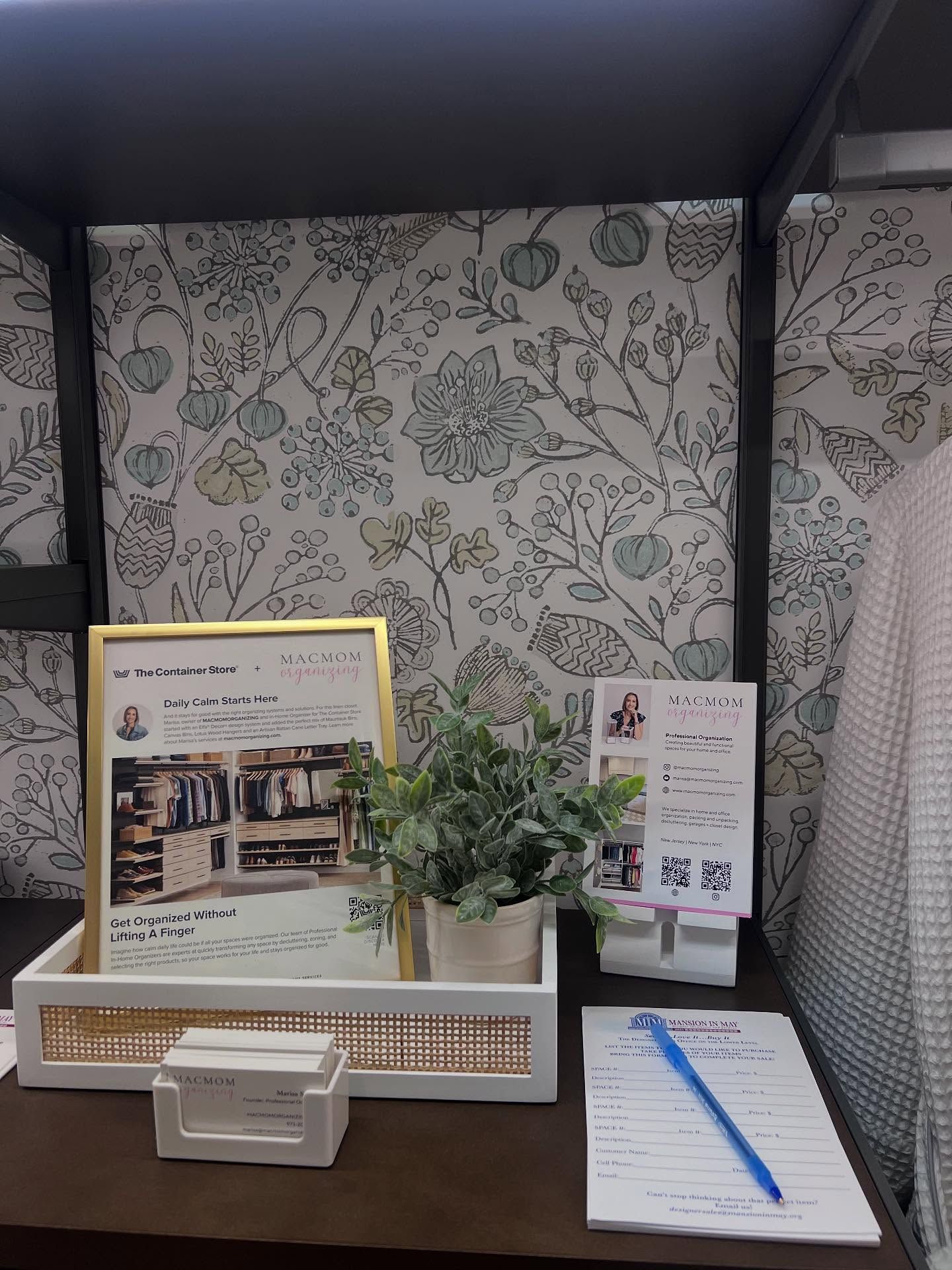 A desk with a plant , a picture frame , and a pen on it.
