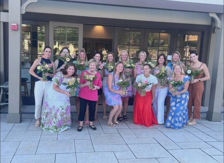 A group of women standing in front of a building holding bouquets of flowers.