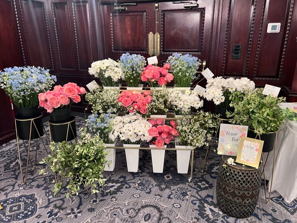 A flower bar with various colorful blooms displayed on tiered shelves, set against a wood-paneled wall.