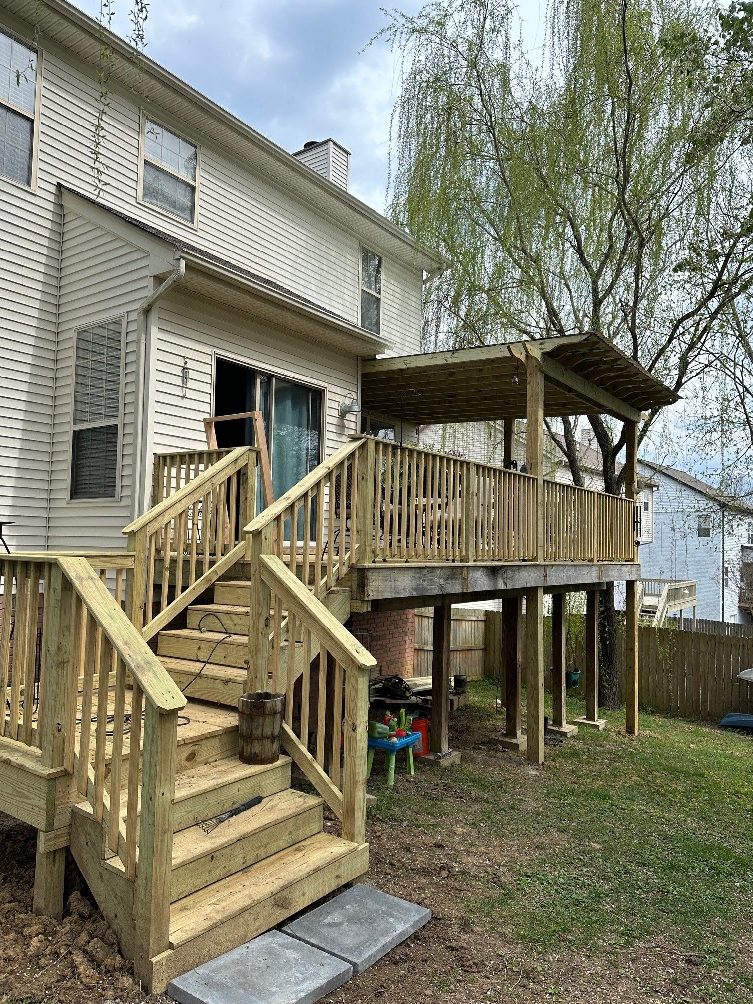 A wooden deck with stairs and a pergola in the backyard of a house