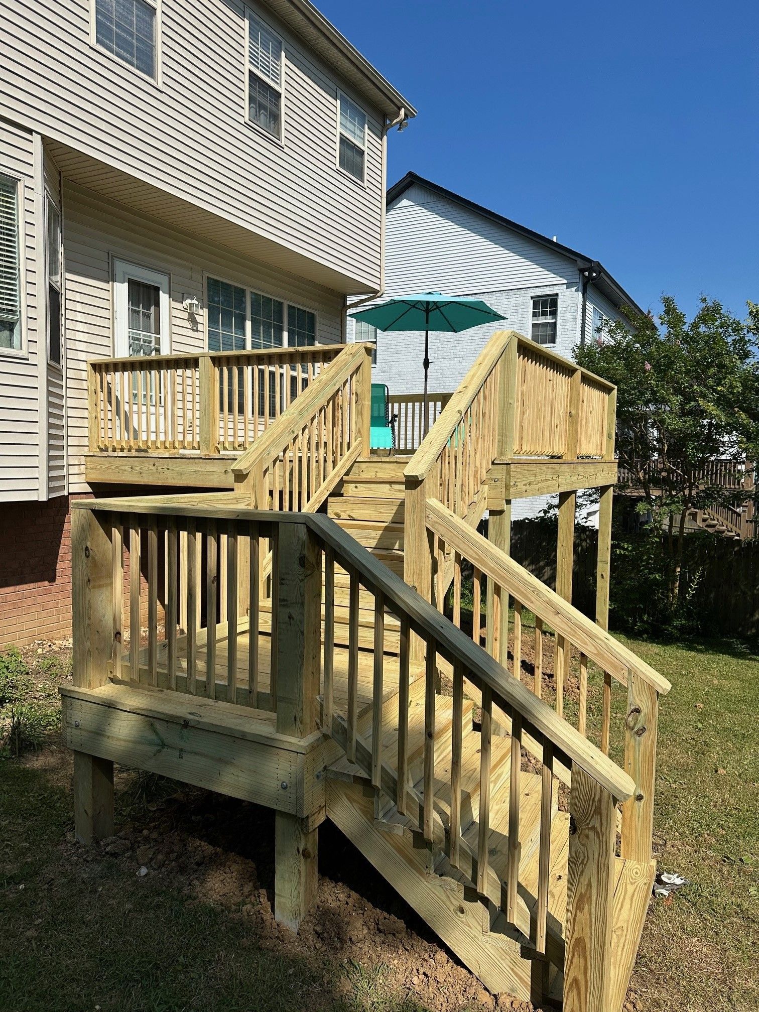 A wooden deck with stairs leading up to it is in the backyard of a house