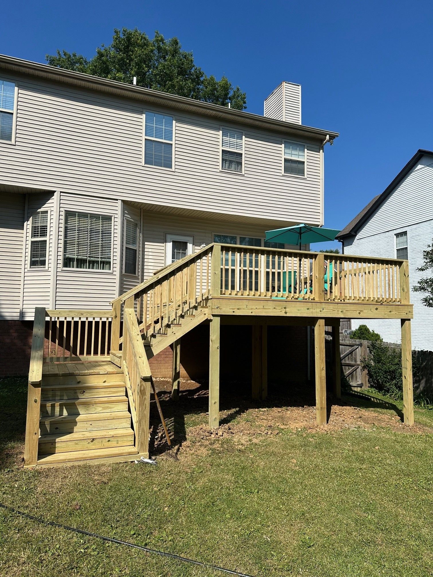 A large wooden deck with stairs is in the backyard of a house
