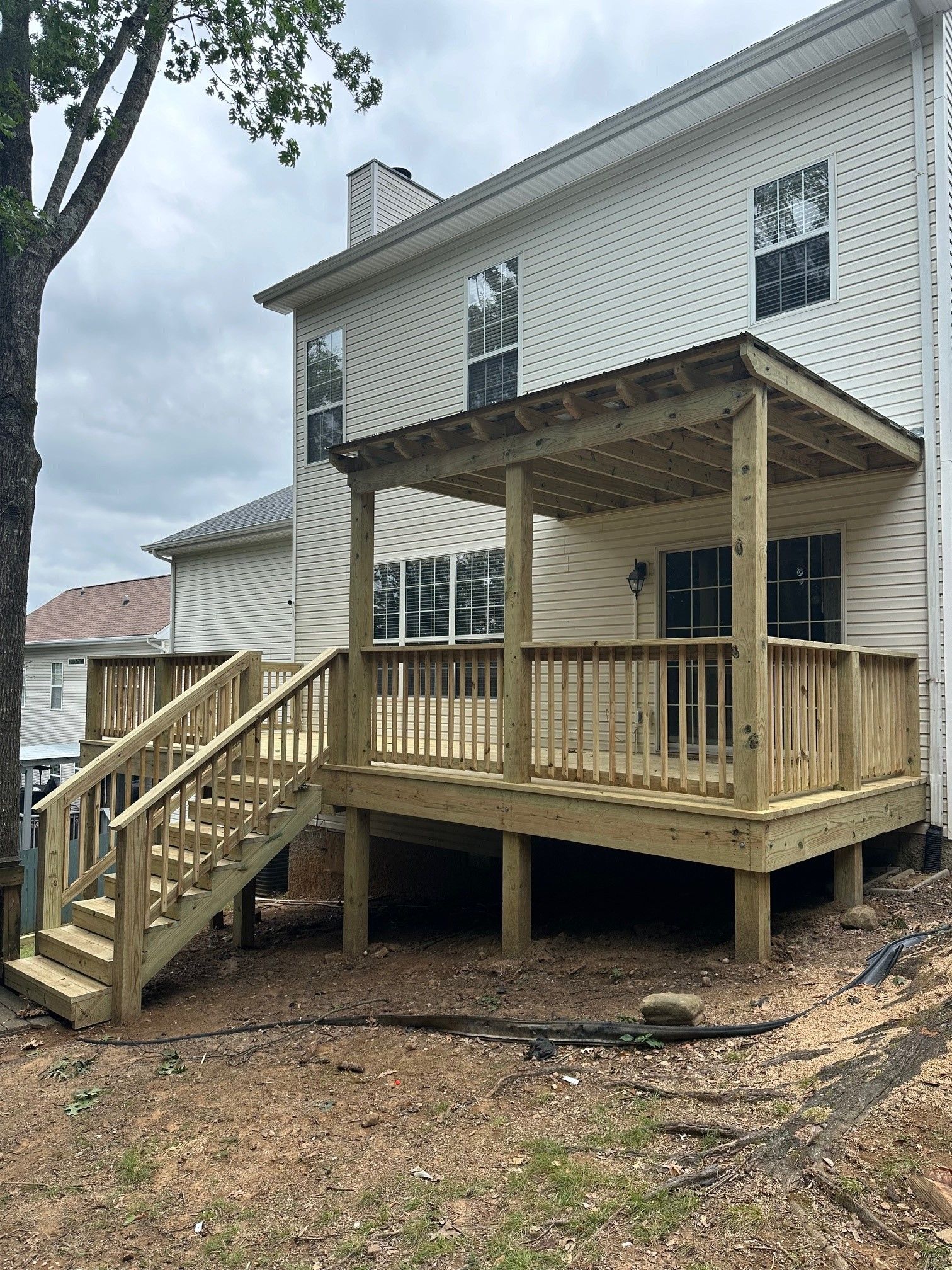 A wooden deck with stairs is in front of a house