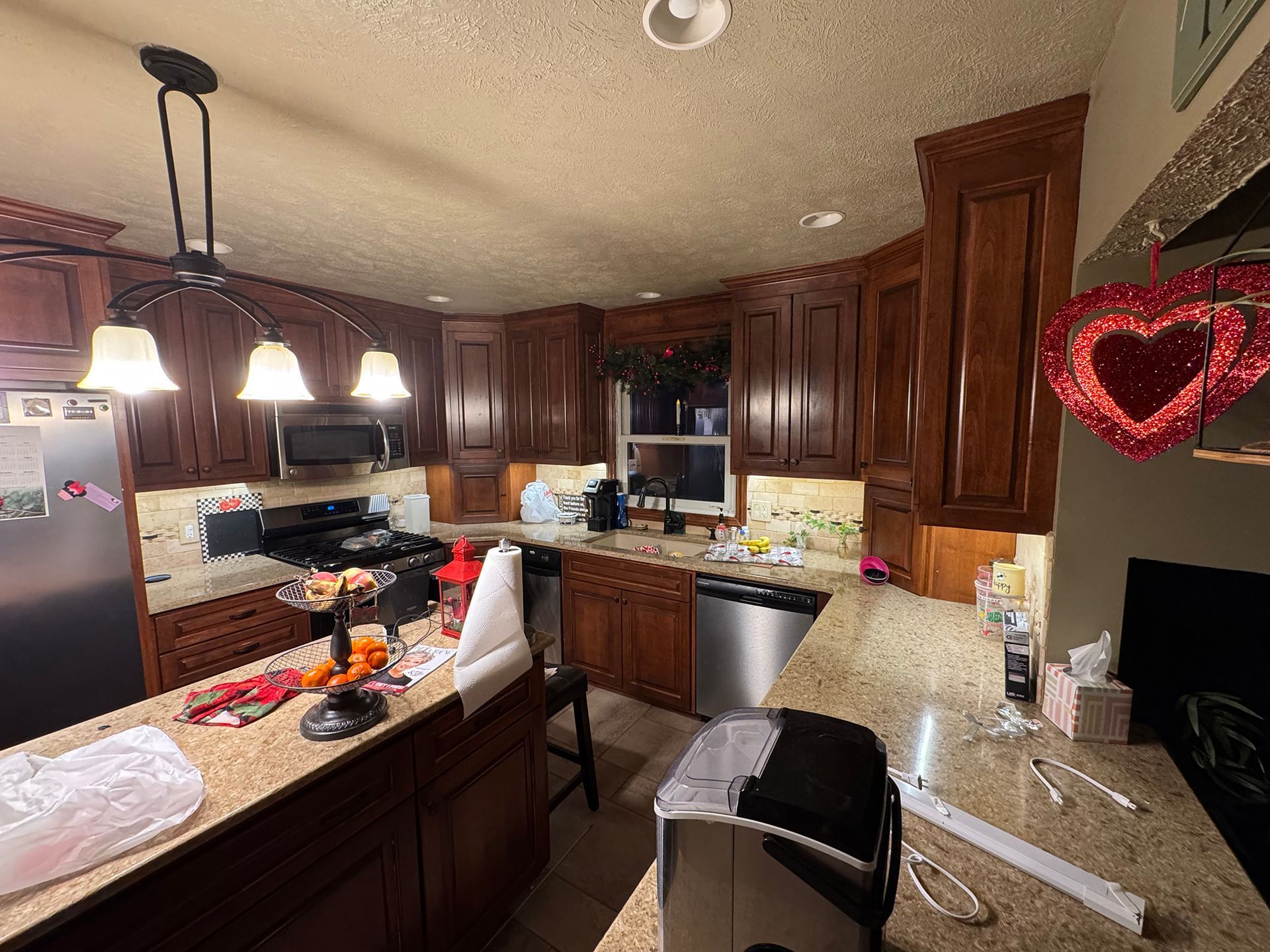 A kitchen with dark wood cabinets, granite countertops, and a stainless steel dishwasher.
