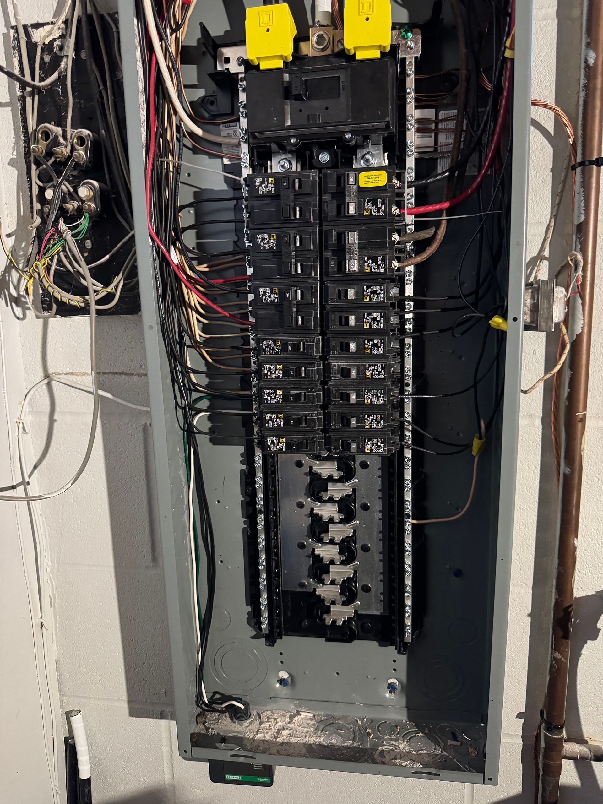 Electrical panel with various circuit breakers and wiring inside a gray metal enclosure.
