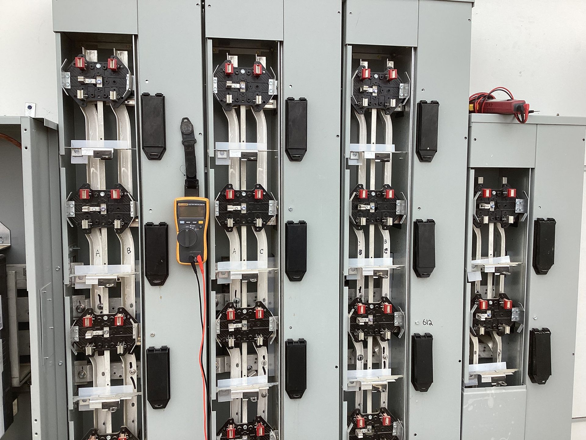 Electrical panel with multiple circuit breakers, open for inspection. A multimeter rests nearby.