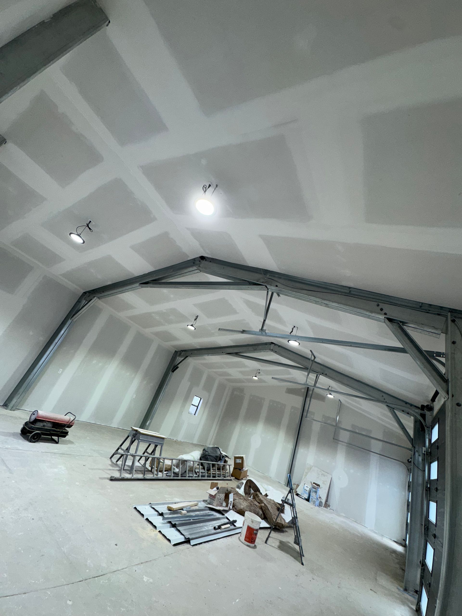 Interior view of a building under construction, featuring exposed steel frame and drywall on the walls and ceiling.
