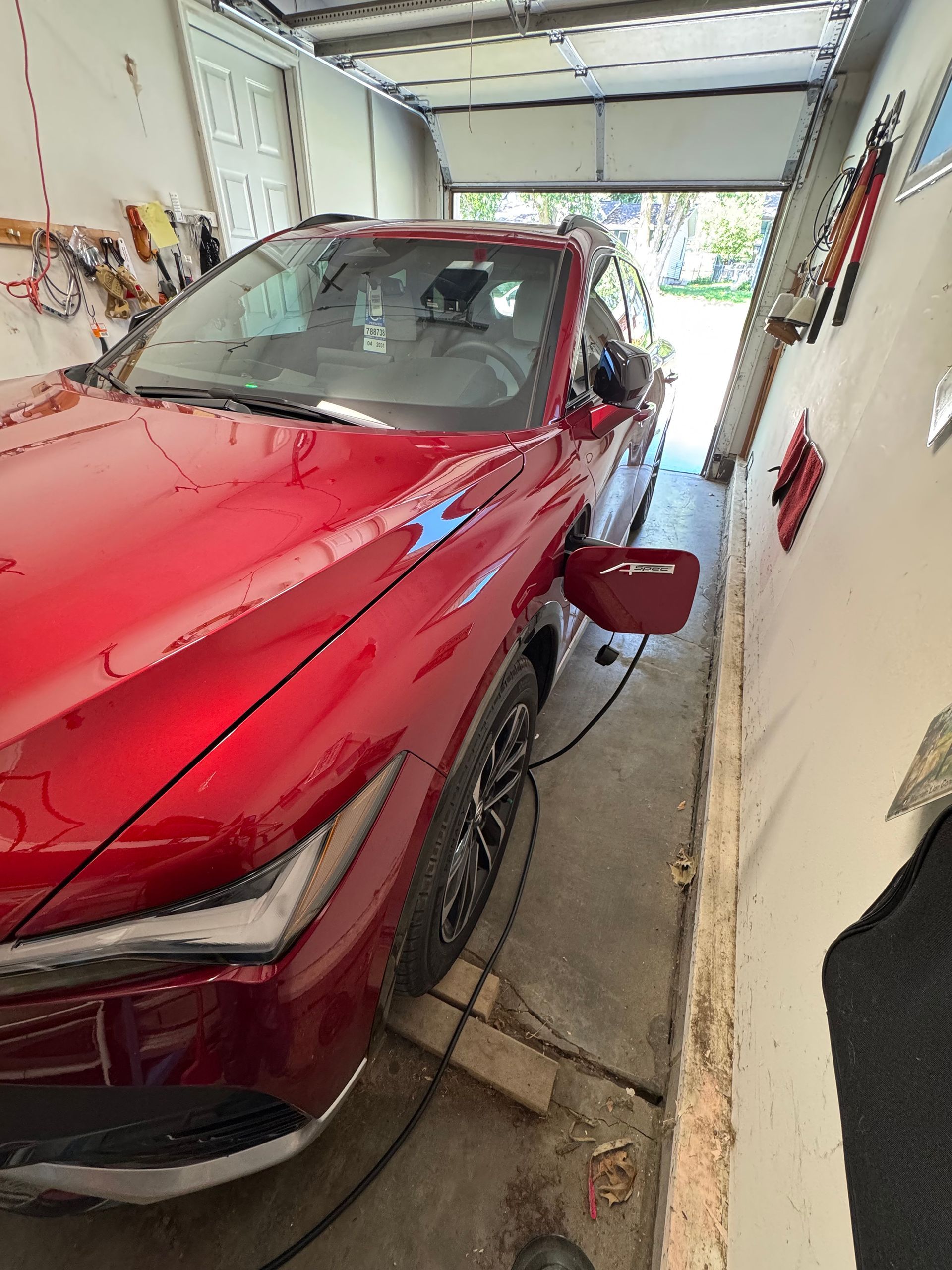 Red SUV parked in a garage, charging cable plugged in with the door open.