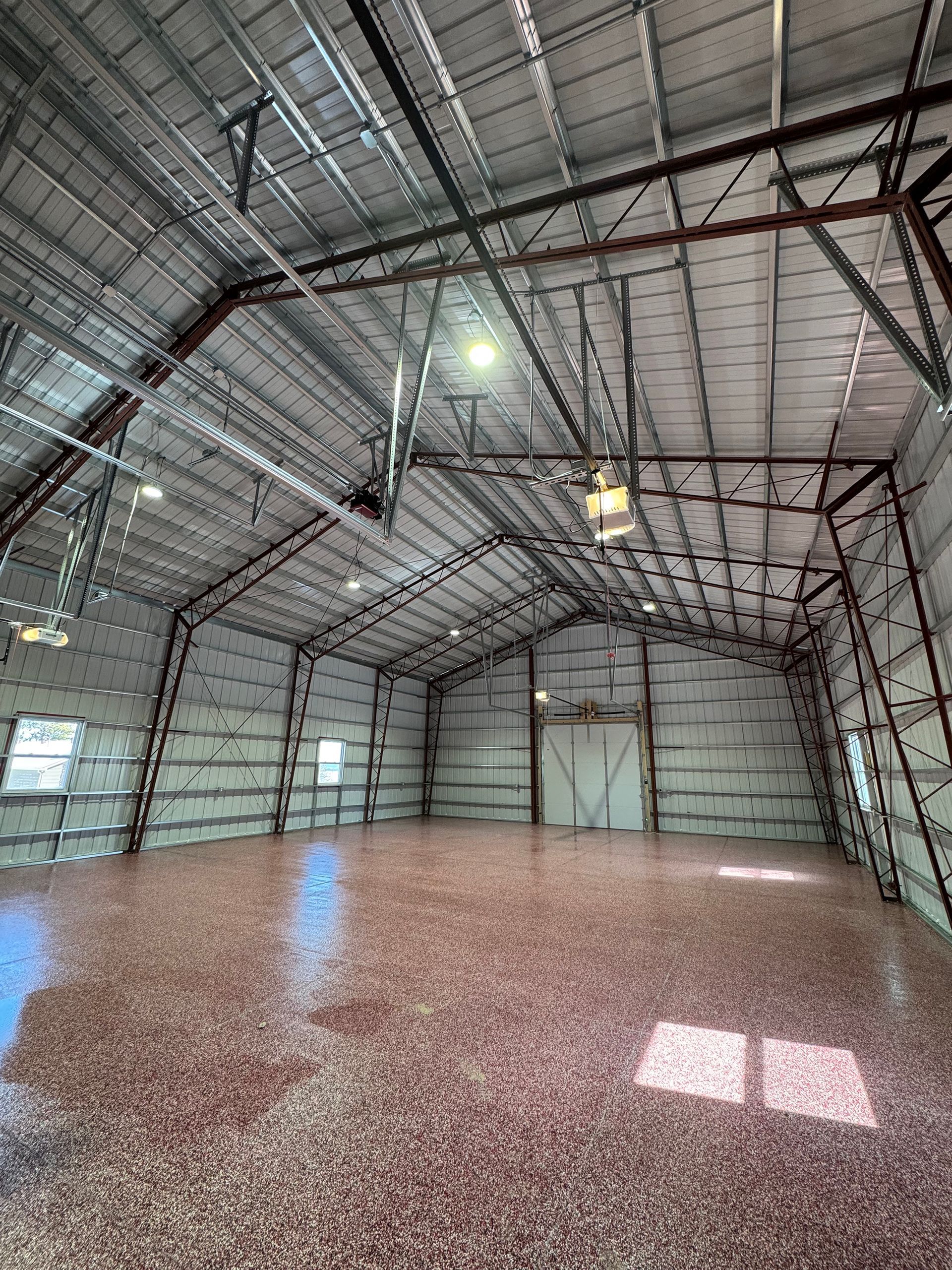Empty industrial building interior with metal frame and speckled floor.