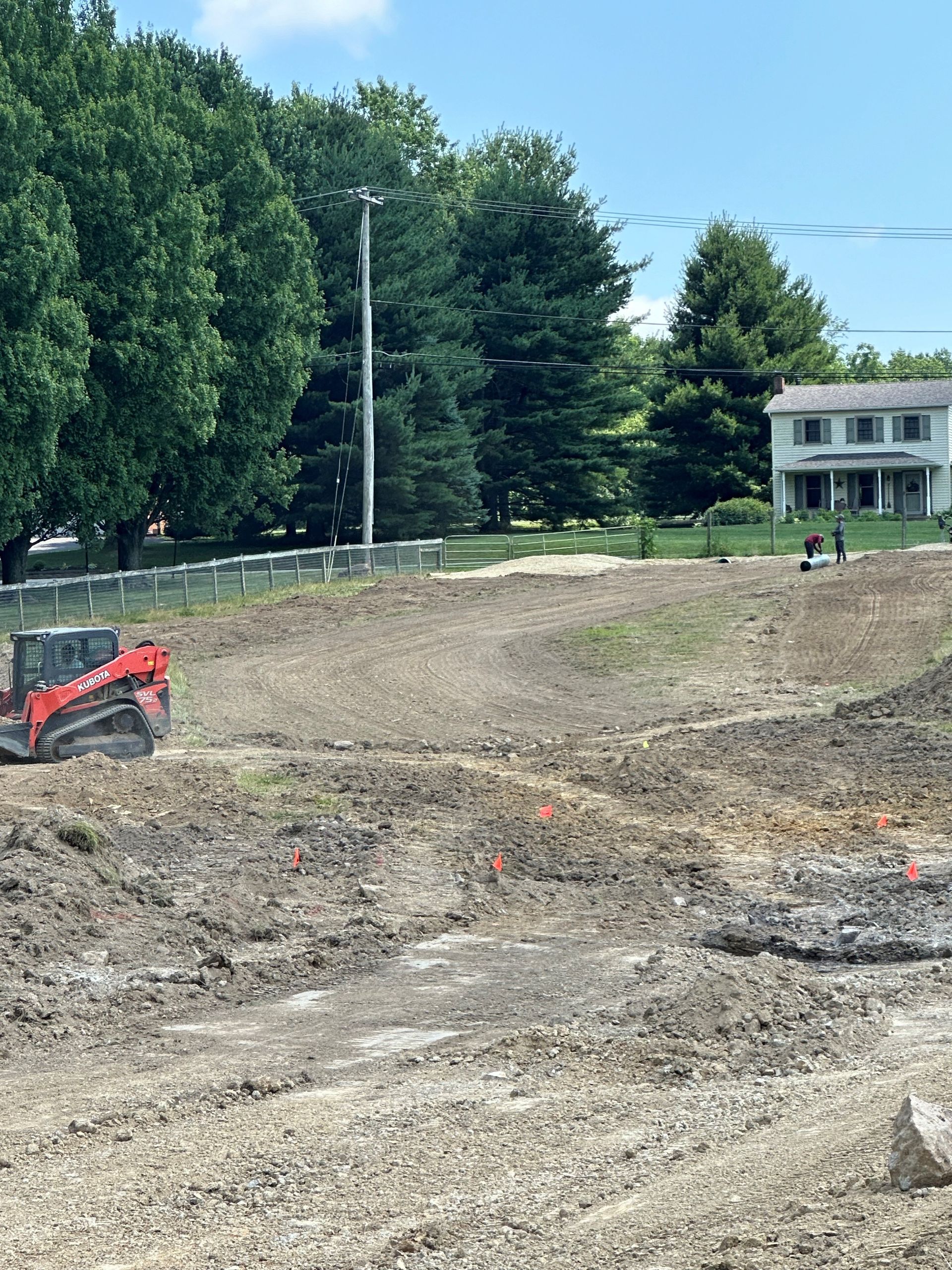 A bulldozer is moving dirt in a field with a house in the background
