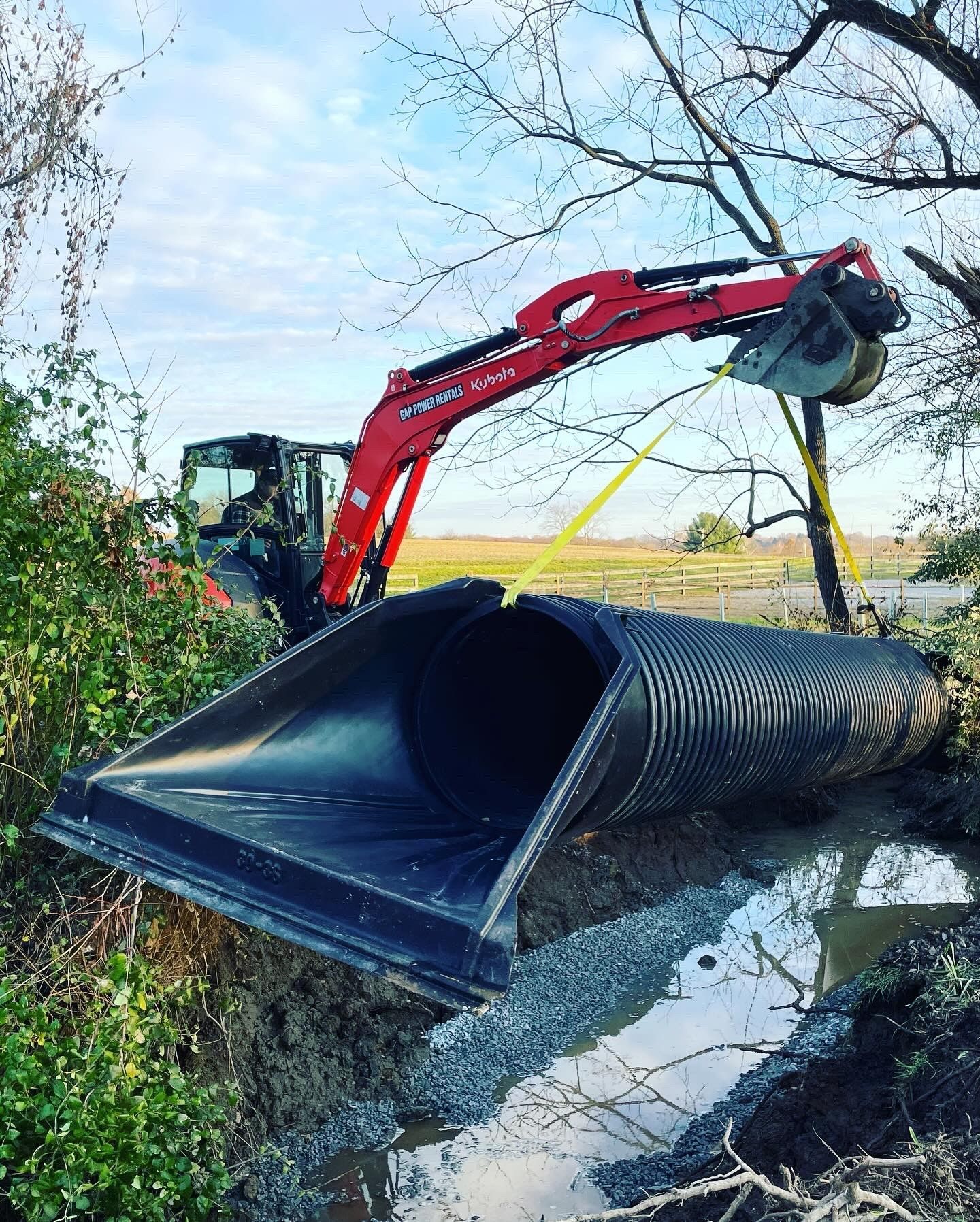 A red and black excavator is digging a hole in the ground