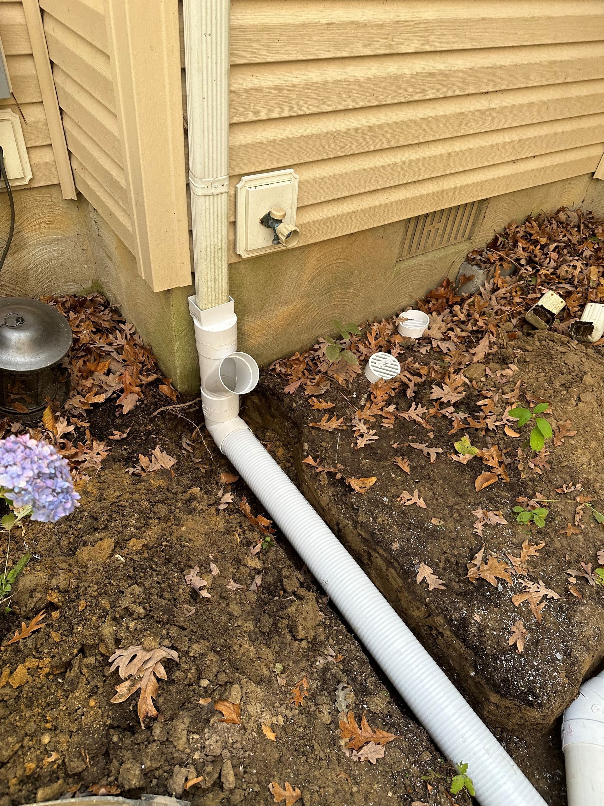 A white pipe is sitting in the dirt next to a house