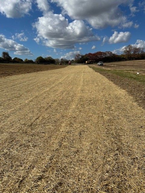 A dirt road with a blue sky and clouds in the background