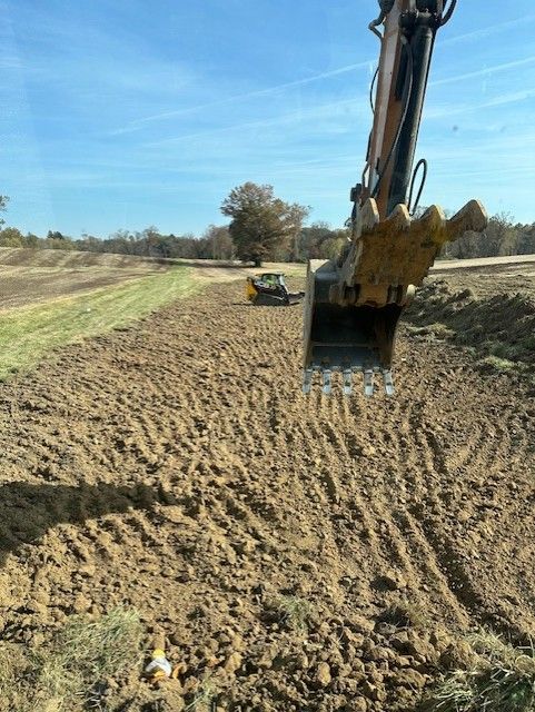 A bulldozer digging a hole in the dirt in a field