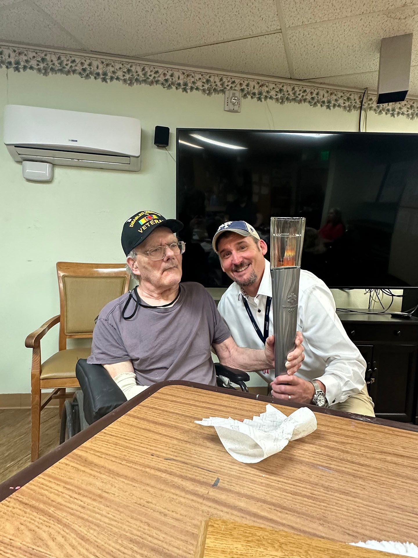 two men are sitting at a table holding a torch