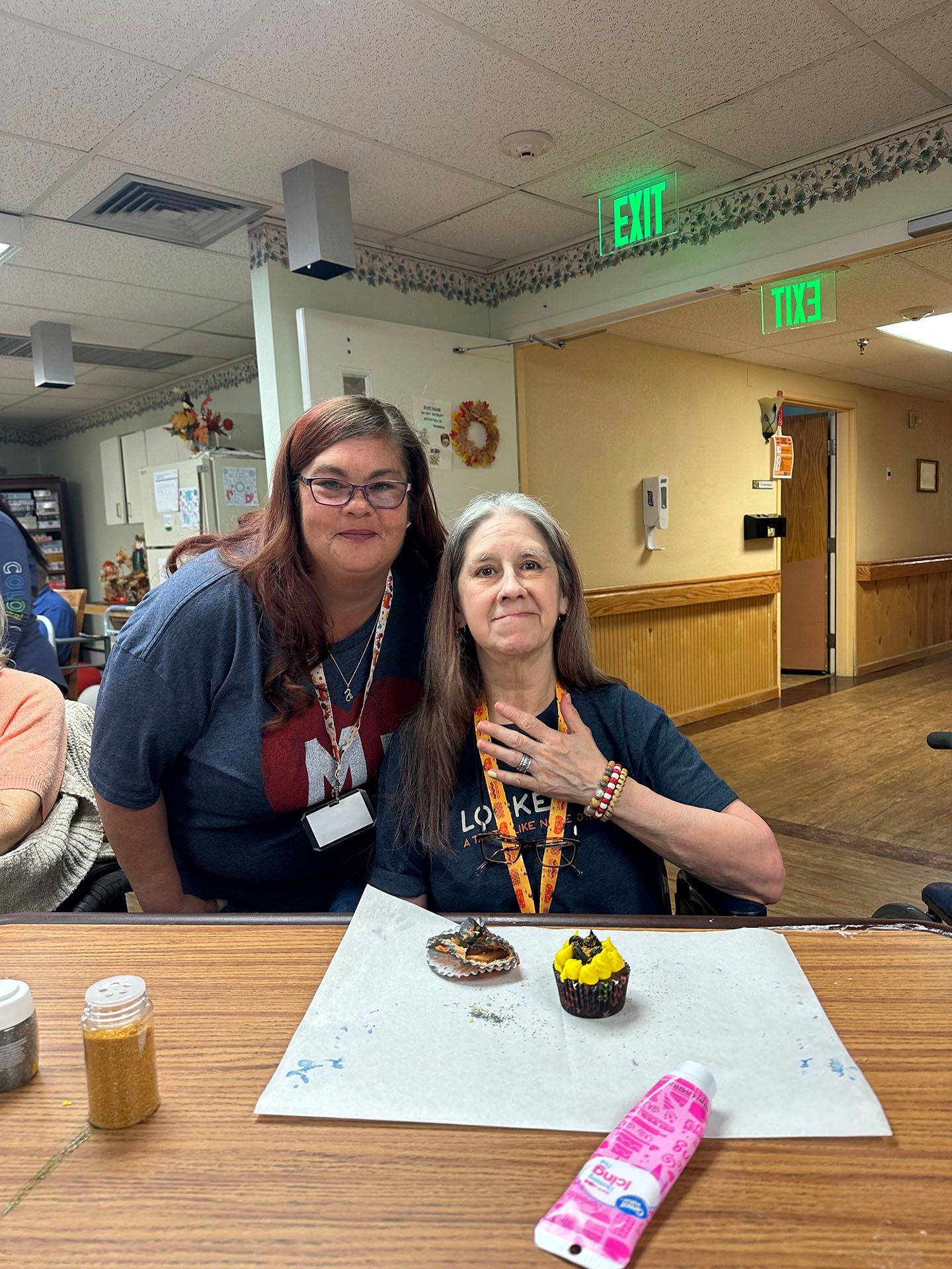 two women are sitting at a table with a cupcake on it