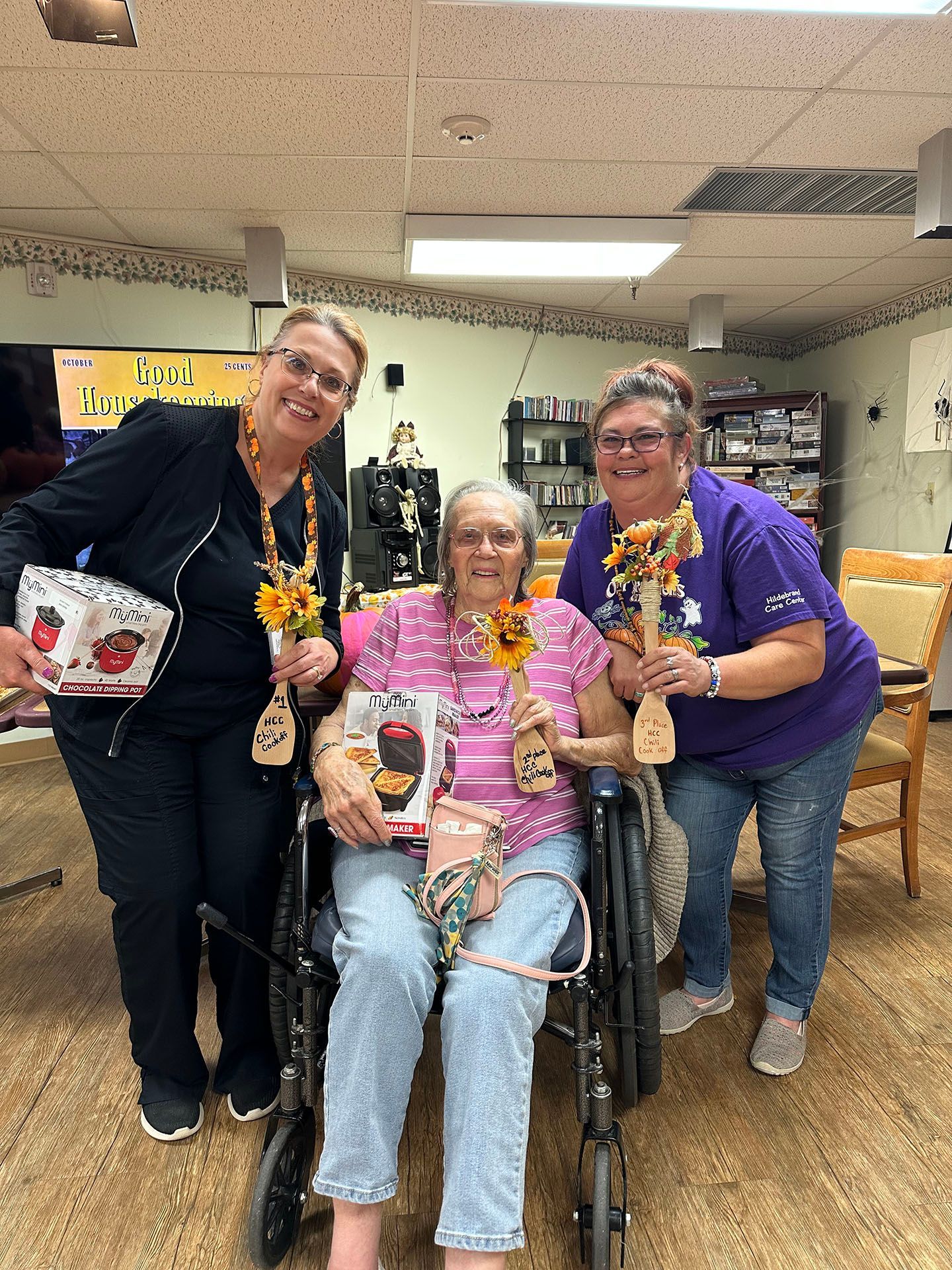 three women are posing for a picture with an elderly woman in a wheelchair