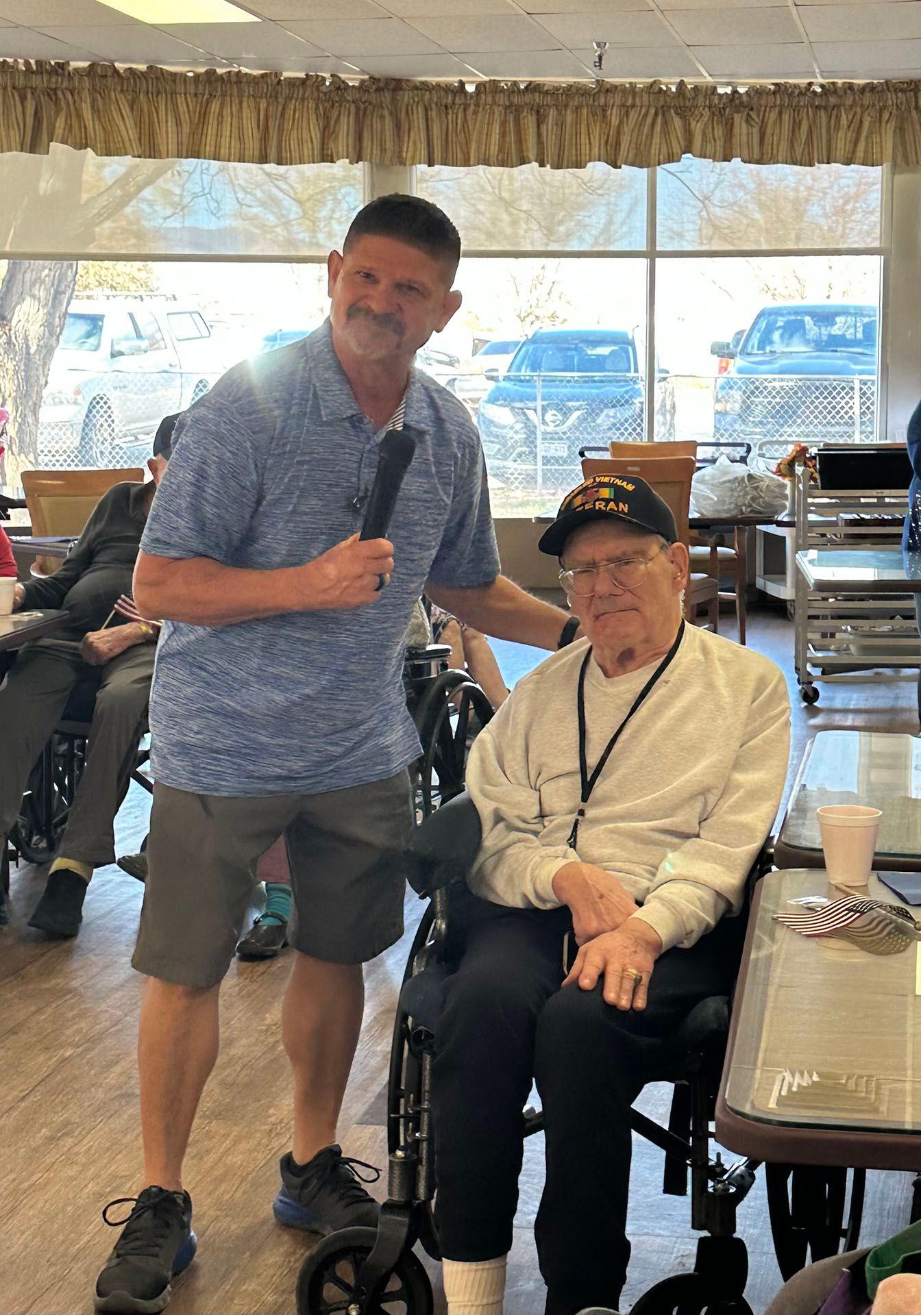 a man is standing next to an older man in a wheelchair