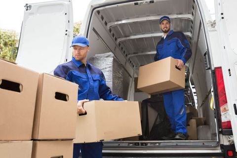 Movers unloading cardboard boxes from a white delivery truck