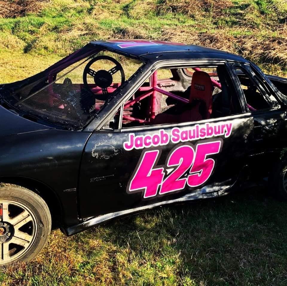 Black race car with Jacob Saulsbury's name and number 425 on side, parked on grass.