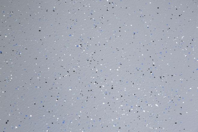 Light gray surface with many small dark specks and scattered white flecks