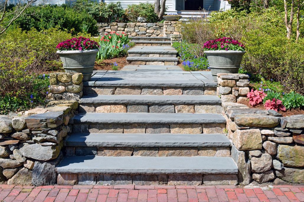 Stone garden steps with flower planters and brick edging leading to a house entrance