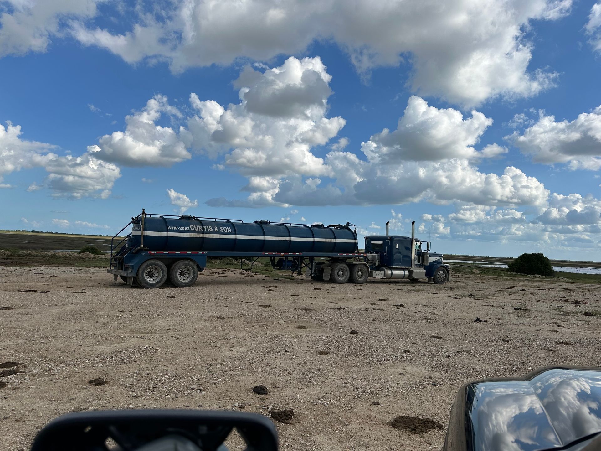 A semi truck is parked in the middle of a dirt field.