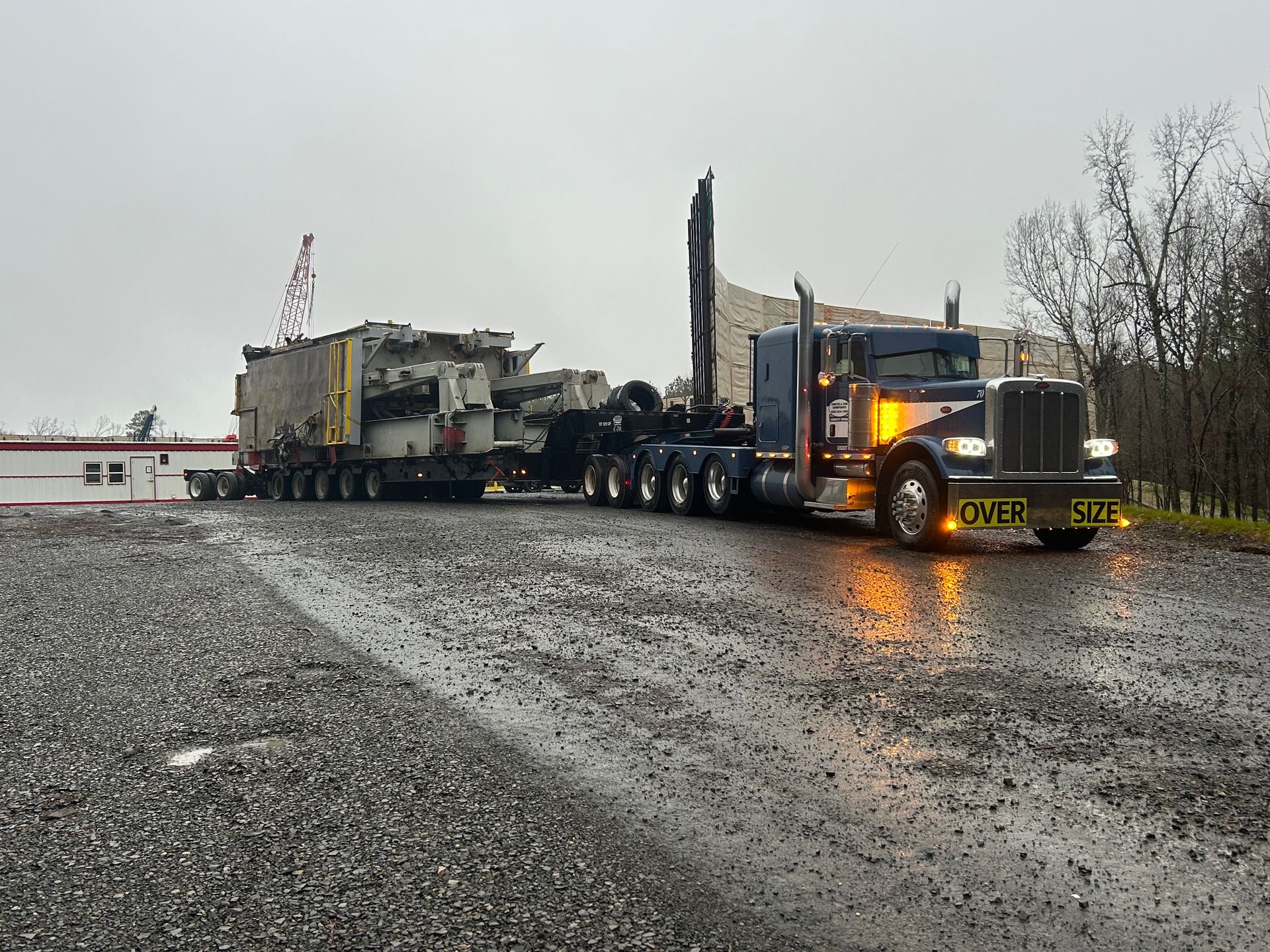 A large semi truck is driving down a wet road.