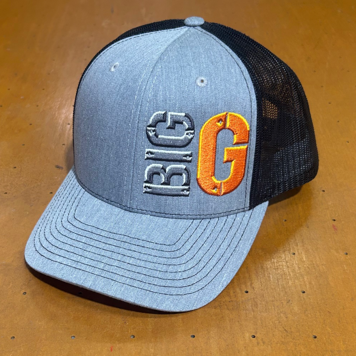 A gray baseball cap with a black mesh back, featuring the embroidered text