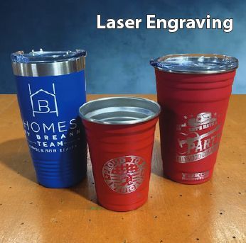 Three tumblers and a red cup with laser-engraved designs on a wooden table