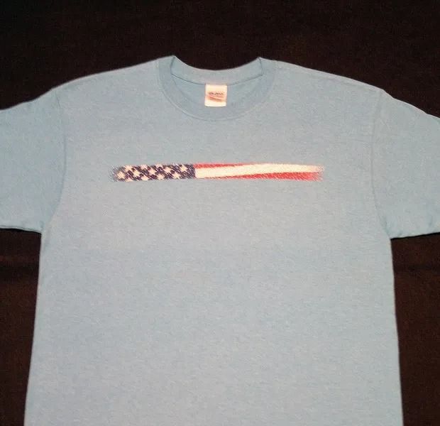 Light blue t-shirt with a horizontally stretched American flag graphic on the chest.